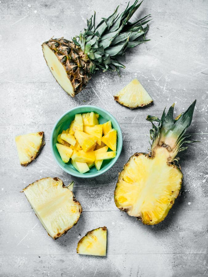 Sliced pineapple in a bowl on a cutting Board with a knife and a whole  pineapple. Stock Photo by Artem_ka2