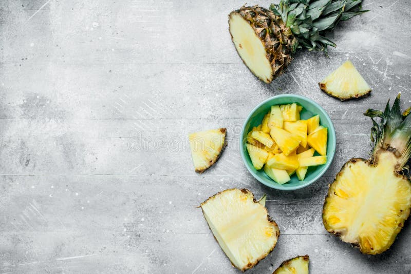 Sliced pineapple in a bowl on a cutting Board with a knife and a whole  pineapple. Stock Photo by Artem_ka2