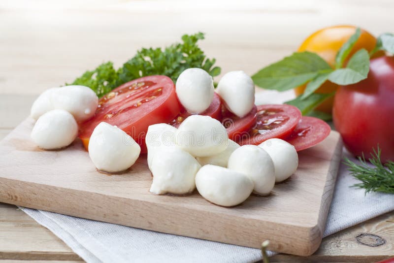 Sliced tomatoes, basil and mozzarella cheese on a wooden board stock image Sliced tomatoes, basil and mozzarella cheese on a wooden board stock image