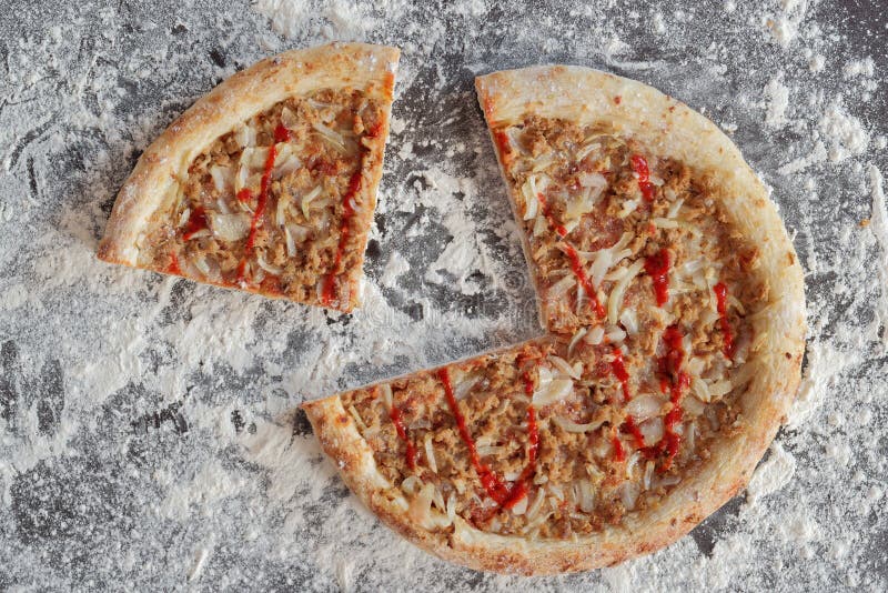 Sliced tuna pizza on background with scattered flour. Sliced tuna pizza on dark background with scattered white flour royalty free stock images Sliced tuna pizza on background with scattered flour. Sliced tuna pizza on dark background with scattered white flour royalty free stock images