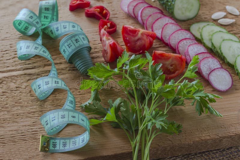 Sliced vegetables and green measuring tape on a blackboard. Low calorie diet concept