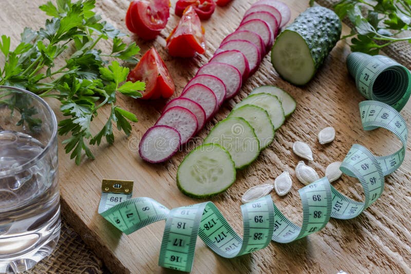 Sliced vegetables and green measuring tape on a blackboard. Low calorie diet concept