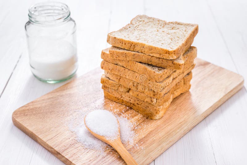 Sliced Whole Wheat Bread with Sugar on White Wooden Table Stock Photo