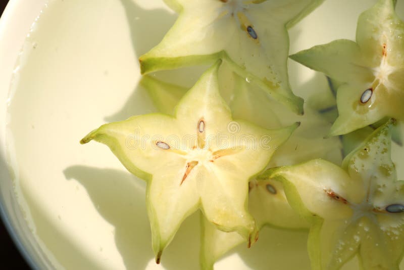 Slices of fresh star fruit. Carambola under sunshine in a bowl filled with water royalty free stock image Slices of fresh star fruit. Carambola under sunshine in a bowl filled with water royalty free stock image