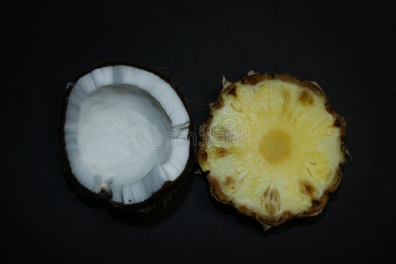 Slices of juicy pineapple and snow-white coconut isolated on a black background. Delicious fruit dessert.