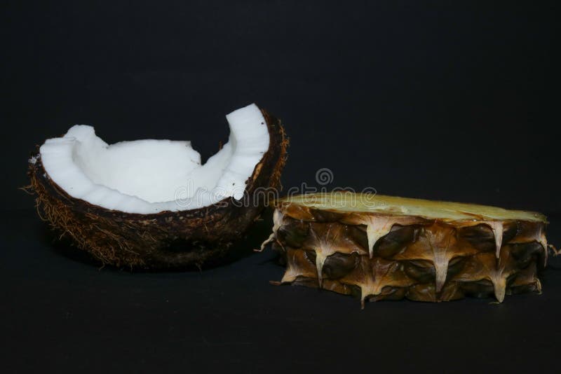 Slices of juicy pineapple and snow-white coconut isolated on a black background. Delicious fruit dessert.