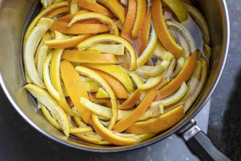 Orange and lemon peels slices and placed in a pan of boiling wather and sugar to make candied peels. Orange and lemon peels slices and placed in a pan of boiling wather and sugar to make candied peels