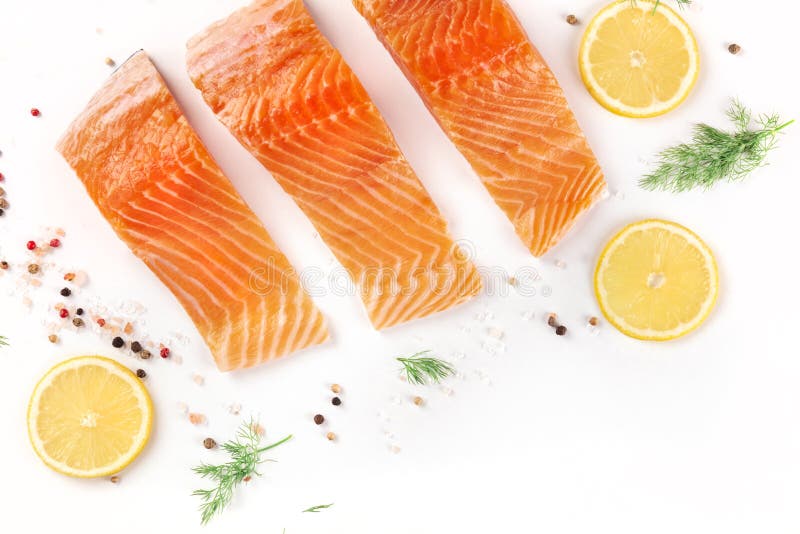 Slices of salmon with lemon and dill, shot from above with salt and pepper on a white background with a place for text. Cooking