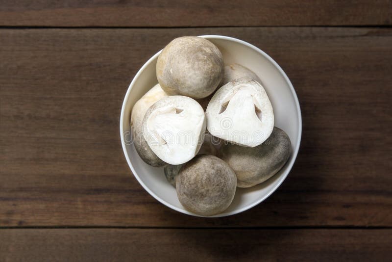 Slices straw mushroom in a white bowl on wooden background, prepare food. royalty free stock photo