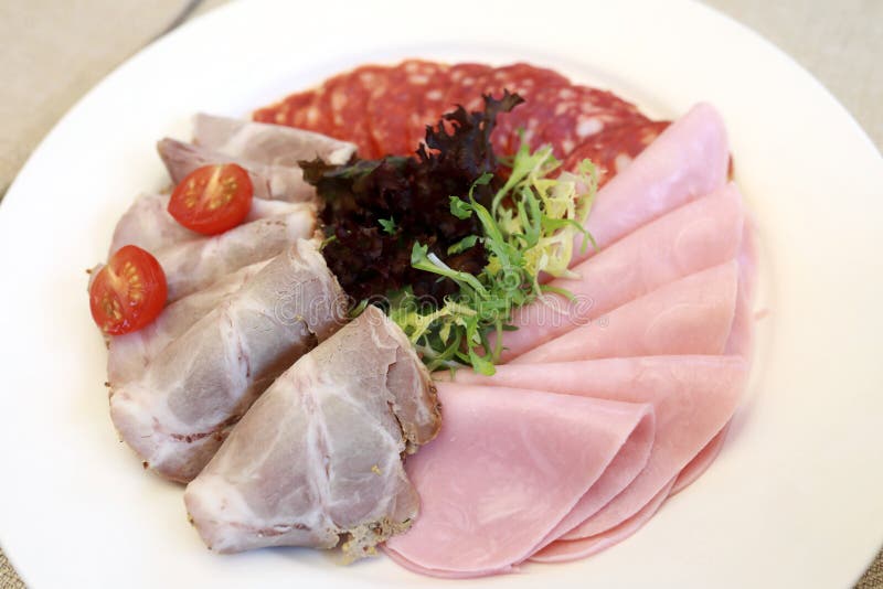 Slices various meat on white plate royalty free stock photography
