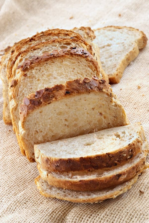 Pagnotta di pane bianco con cereali integrali, tagliato a pezzi per la preparazione di toast e panini.