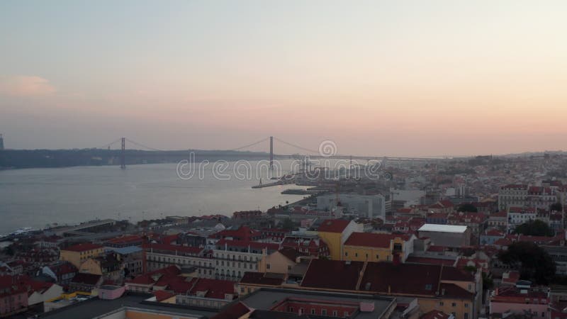 Slider vista aérea de ponte 25 de abril puente rojo en lisboa portugal con tejados de casas en el centro de la ciudad en el almacen de video