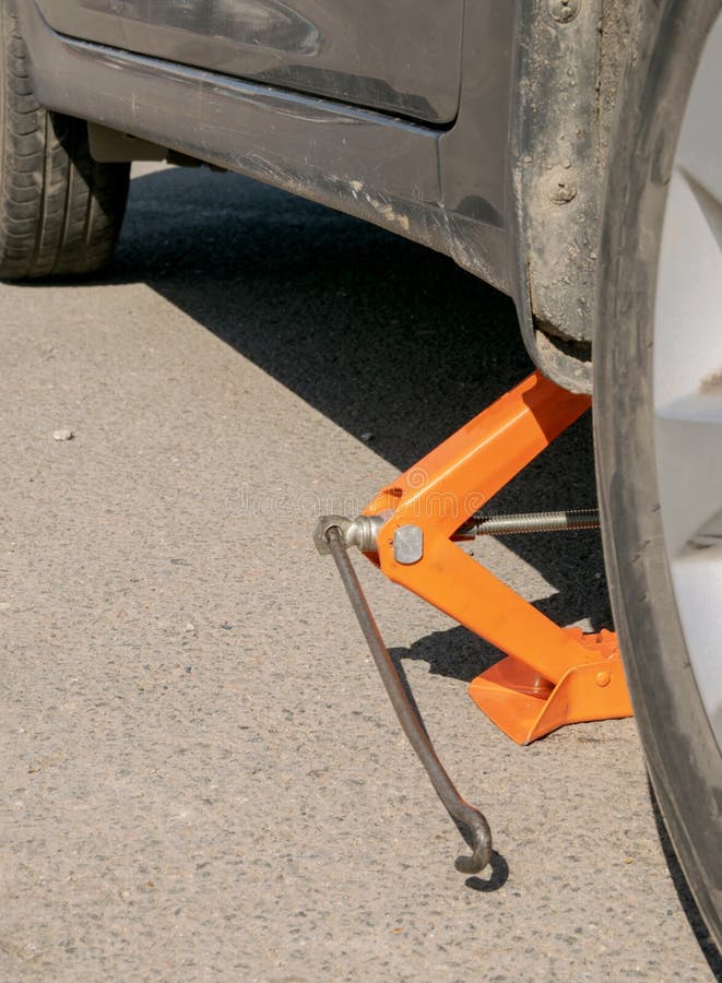 Slightly Lifted Gray Auto with Orange Repair Jack Stock Photo Image