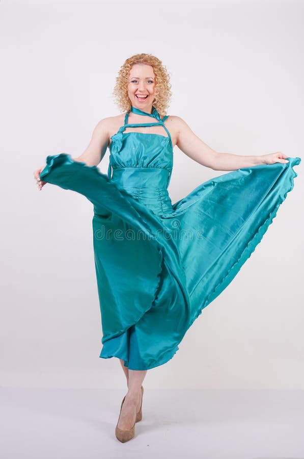 Slim airy girl in flying blue evening dress on white background in Studio royalty free stock image Slim airy girl in flying blue evening dress on white background in Studio royalty free stock image
