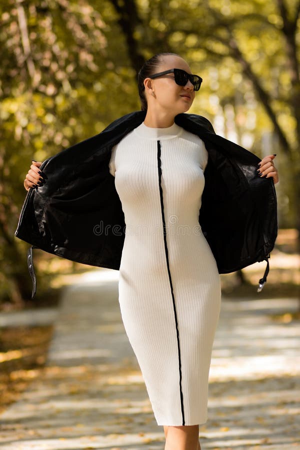 Stylish woman taking off jacket in park