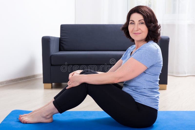 Slim sporty mature woman doing exercises on yoga mat at home royalty free stock image Slim sporty mature woman doing exercises on yoga mat at home royalty free stock image