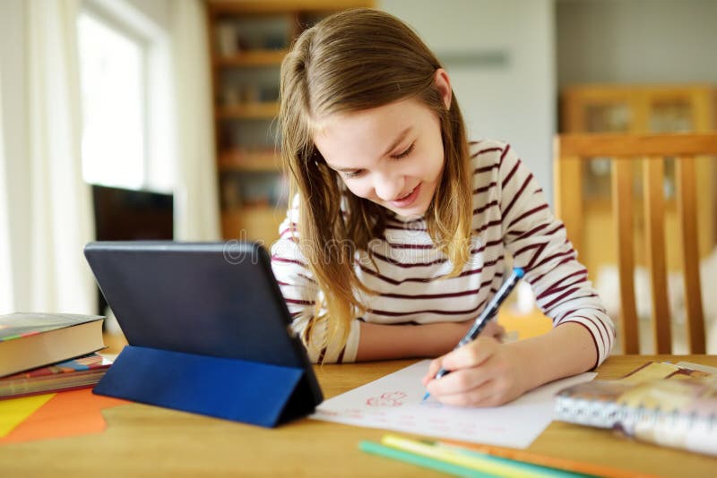 Slim voorschoolmeisje dat haar huiswerk doet met digitale tablet thuis. onderwijs en afstandsonderwijs voor kinderen. huiskeuze