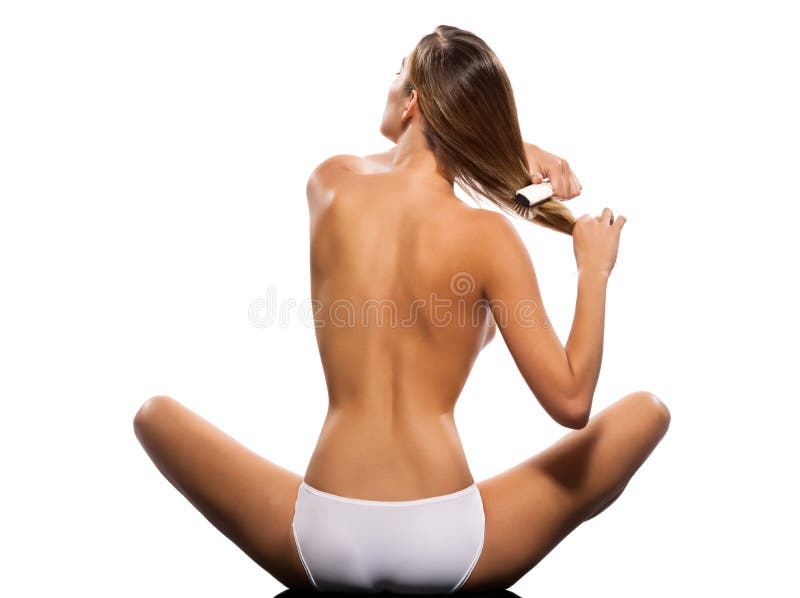 Rear view of a topless slim woman brushing hair on isolated white background. Rear view of a topless slim woman brushing hair on isolated white background