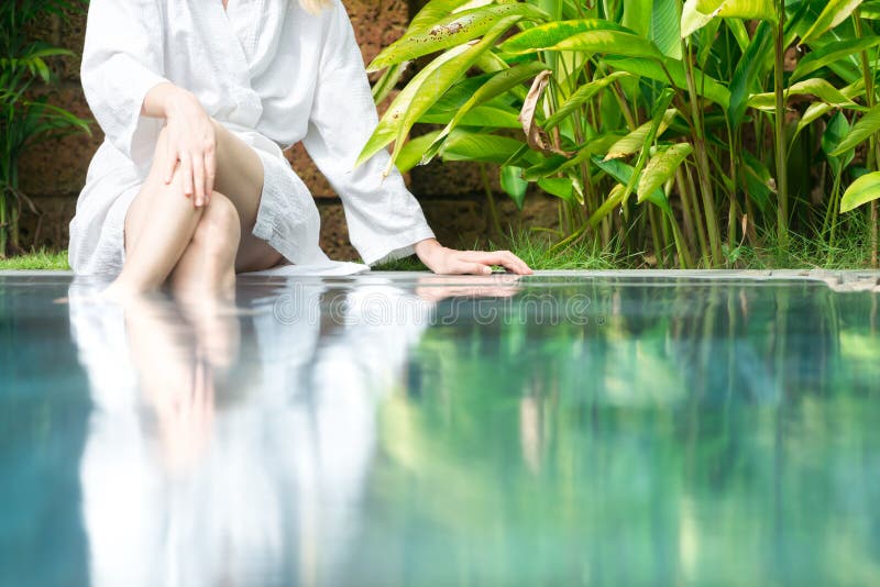 Woman resting at pool with feet in water.