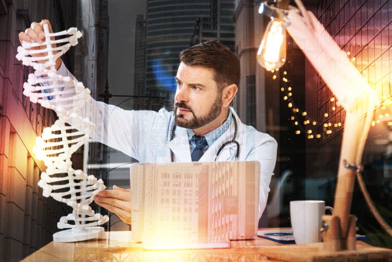 Slimme geneticus die een groot DNA-model houden terwijl het zijn op het werk stock fotografie Slimme geneticus die een groot DNA-model houden terwijl het zijn op het werk stock fotografie