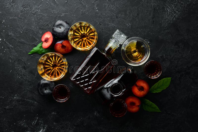 Slivovica - plum vodka, plum brandy in a bottle on a black stone table. Glasses with alcoholic beverage. Top view. Free space for your text stock photos Slivovica - plum vodka, plum brandy in a bottle on a black stone table. Glasses with alcoholic beverage. Top view. Free space for your text stock photos