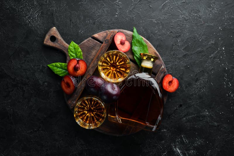 Slivovica - plum vodka, plum brandy in a bottle on a black stone table. Glasses with alcoholic beverage. Top view. Free space for your text stock photos Slivovica - plum vodka, plum brandy in a bottle on a black stone table. Glasses with alcoholic beverage. Top view. Free space for your text stock photos