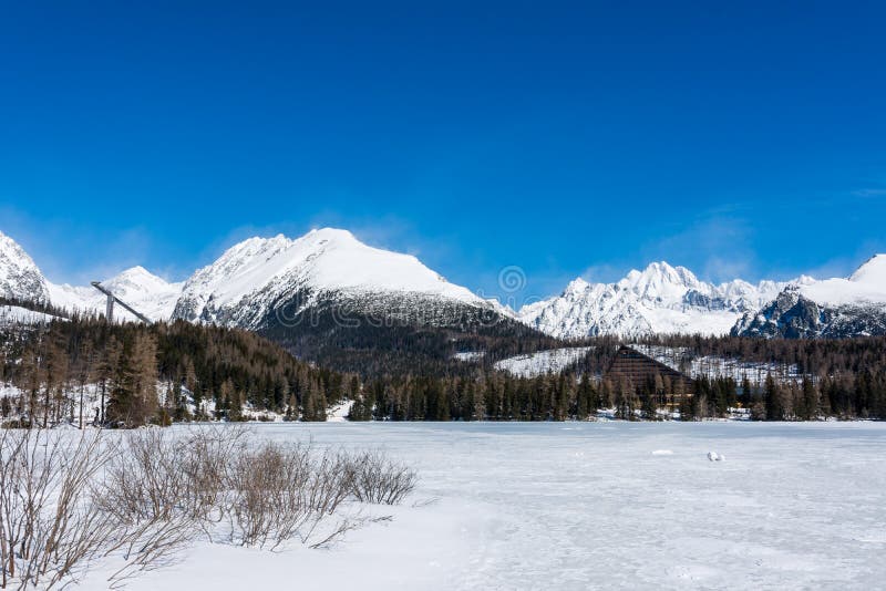 Slovensko, Štrbské Pleso: Pohled na zamrzlé jezero ve Velkých Tatrách na Slovensku. Hory v pozadí, stromy a jezero v popředí. Wi