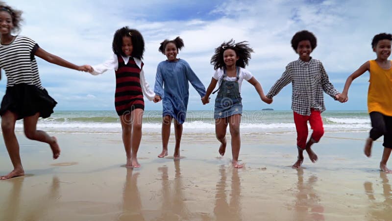 Slow motion, African-American children are holding hands running on the beach in the summer stock video footage