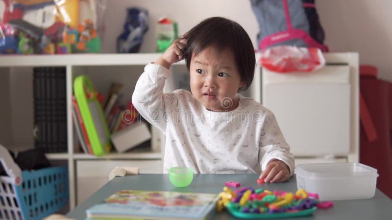 Slow motion of Asian Chinese Toddler scratching her head in confusion