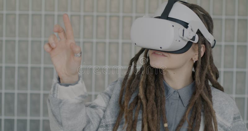 Slow motion of girl with dreadlocks having fun with virtual reality glasses using gaming device gesturing indoors stock video