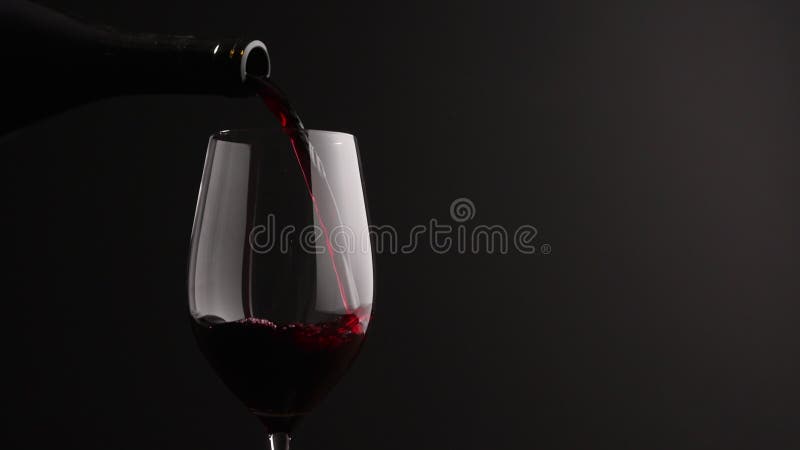 Slow motion pour red wine into wineglass on black background stock video footage