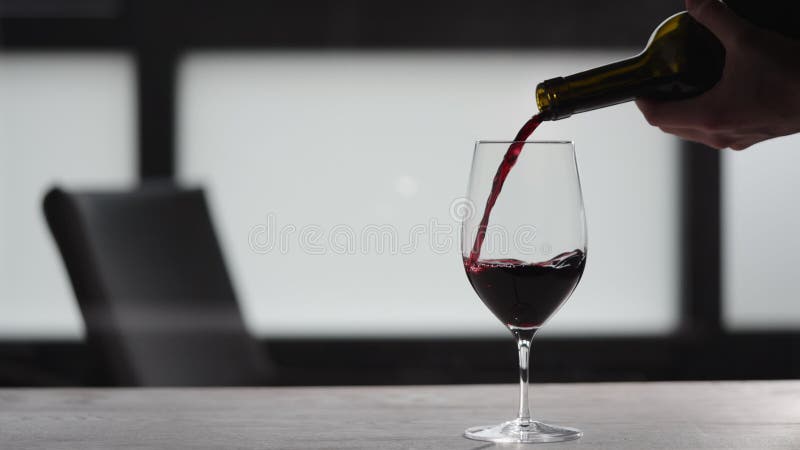 Slow motion pour red wine into wineglass on white oak table with copy space stock footage