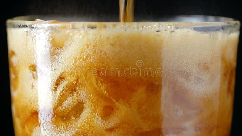 Slow motion pouring cola soda rootbeer mixed water in to the glass with ice