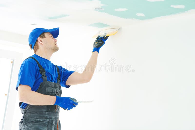 Refurbishment. Plasterer spackling a gypsum plasterboard ceiling with putty