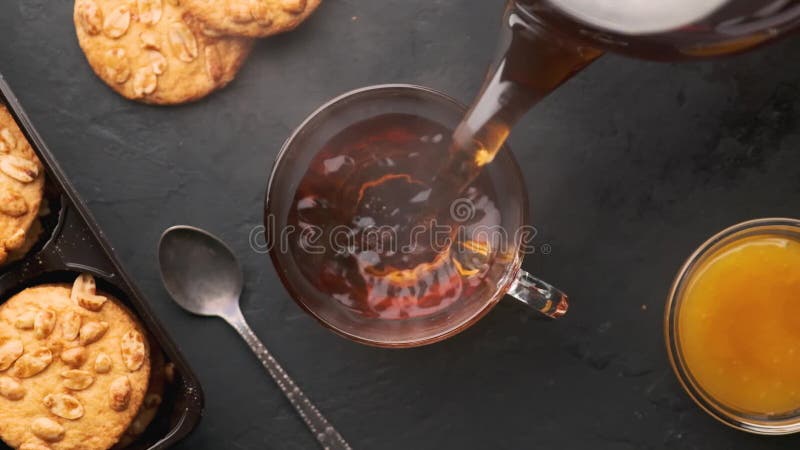 Slow motion, top view, hot tea is poured into a cup on a black table and slowly emits steam. Hot cafe video