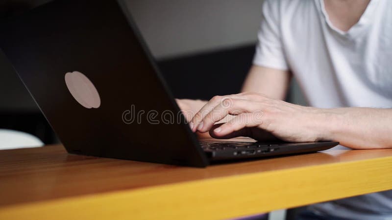 Slow motion video. Young man using laptop. Guy hands typing at computer keyboard