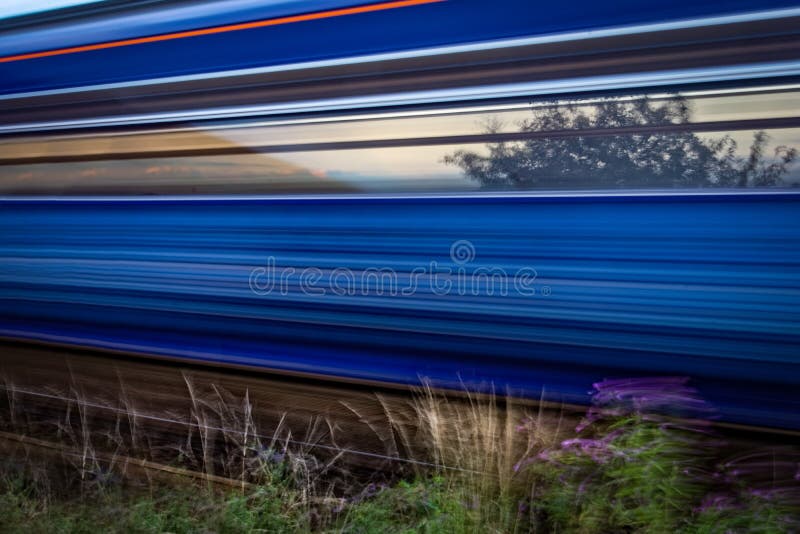 Slow shutter shot of blue and red train speeding past