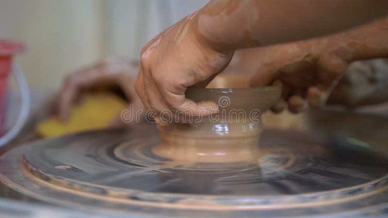 Slowmotion съемка крупного плана гончара учителя уча его подмастерью как сделать шар глины на колесе гончара акции видеоматериалы