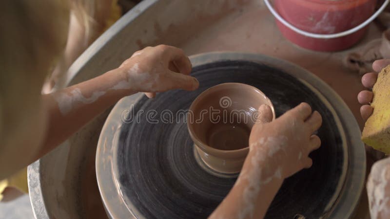 Slowmotion съемка крупного плана гончара учителя уча его подмастерью как сделать шар глины на колесе гончара видеоматериал