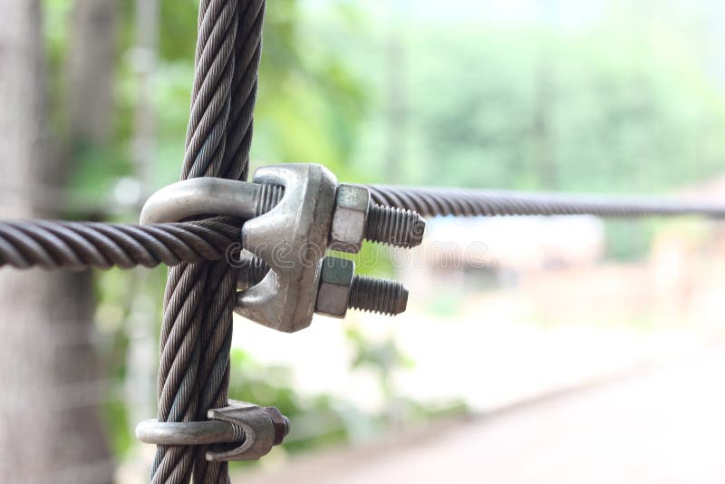 Close up wire rope clips on the bridge with green blur background. Close up wire rope clips on the bridge with green blur background. Close up wire rope clips on the bridge with green blur background. Close up wire rope clips on the bridge with green blur background.