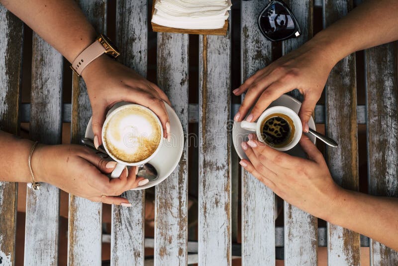 Sluit de verticale weergave van een paar vrouwelijke caucasiaanse vrienden die een koffie en cappuccino hebben, bij elkaar in de