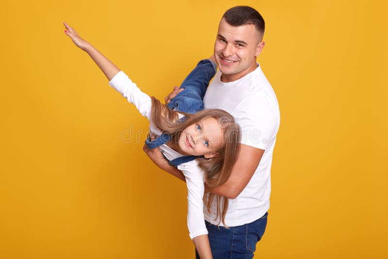 Sluit het portret van een kind dat met haar vader speelt, een meisje dat aan vaders handen zit, doet alsof ze vliegt, wapens zijw stock afbeeldingen Sluit het portret van een kind dat met haar vader speelt, een meisje dat aan vaders handen zit, doet alsof ze vliegt, wapens zijw stock afbeeldingen