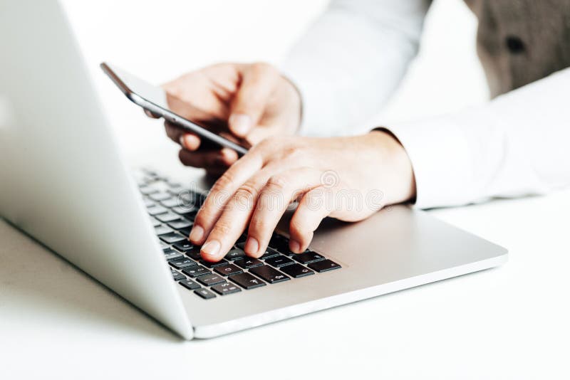Sluit omhoog beeld van multitasking bedrijfsmens gebruikend laptop en een mobiele telefoon royalty-vrije stock foto Sluit omhoog beeld van multitasking bedrijfsmens gebruikend laptop en een mobiele telefoon royalty-vrije stock foto