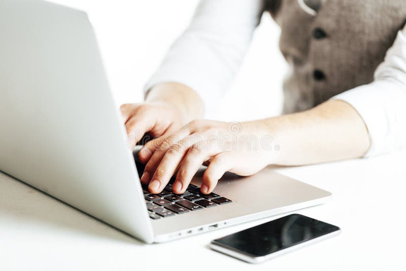Sluit omhoog beeld van multitasking bedrijfsmens gebruikend laptop en een mobiele telefoon royalty-vrije stock afbeeldingen Sluit omhoog beeld van multitasking bedrijfsmens gebruikend laptop en een mobiele telefoon royalty-vrije stock afbeeldingen
