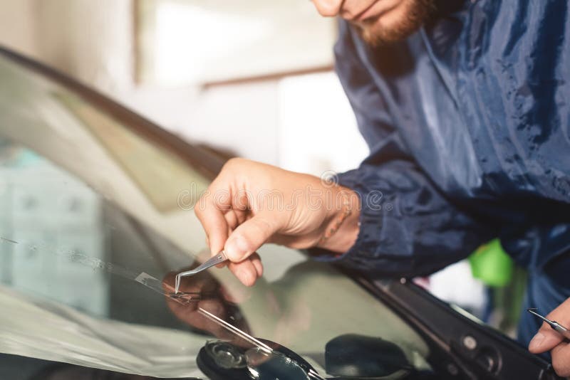 Sluit omhoog de arbeider die van de Autoglans en een windscherm of windscherm van een auto bevestigen herstellen bij een garagebe royalty-vrije stock afbeeldingen Sluit omhoog de arbeider die van de Autoglans en een windscherm of windscherm van een auto bevestigen herstellen bij een garagebe royalty-vrije stock afbeeldingen