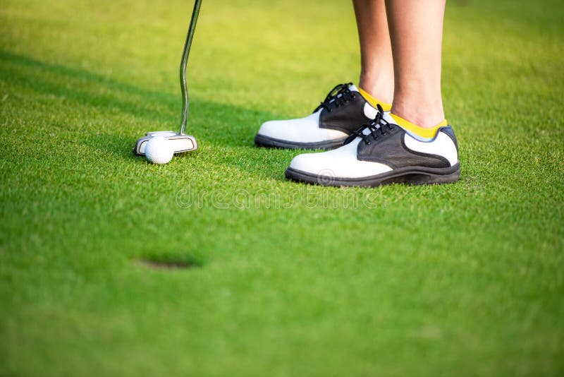 Sluit omhoog de benaderingsgolfbal van golfspelerbenen zettend op groen, stock afbeelding Sluit omhoog de benaderingsgolfbal van golfspelerbenen zettend op groen, stock afbeelding