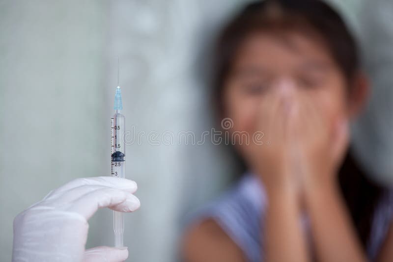 Sluit omhoog de holdingsspuit van de artsenhand met een vrees van het kindmeisje stock afbeeldingen Sluit omhoog de holdingsspuit van de artsenhand met een vrees van het kindmeisje stock afbeeldingen