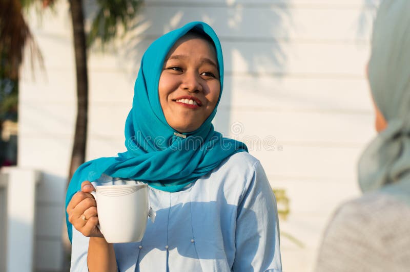 Sluit omhoog gelukkige geschotene twee hijabvrouwen die thee voor het huis en het glimlachen drinken royalty-vrije stock afbeelding Sluit omhoog gelukkige geschotene twee hijabvrouwen die thee voor het huis en het glimlachen drinken royalty-vrije stock afbeelding