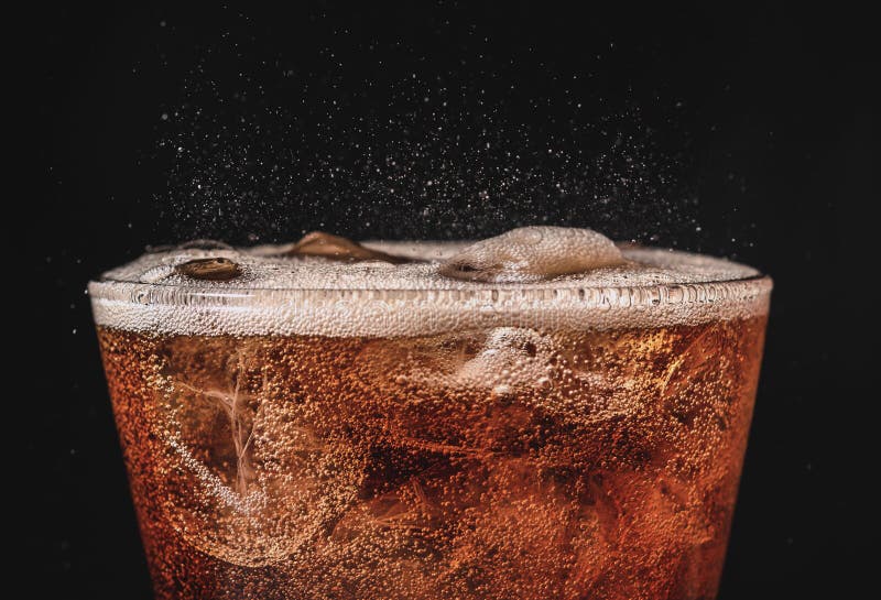 close up ice cola in glass and bubble soda splashing on black background. close up ice cola in glass and bubble soda splashing on black background