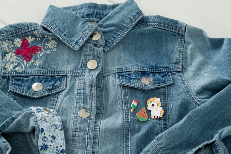 Sluit omhoog mening van het jasje van denimjeans met koele grafische spelden royalty-vrije stock afbeeldingen Sluit omhoog mening van het jasje van denimjeans met koele grafische spelden royalty-vrije stock afbeeldingen